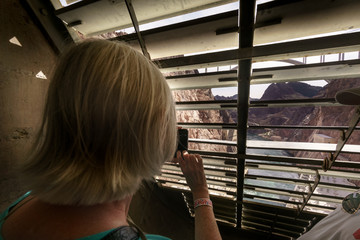 Head and shoulders shot of woman photographing view through shutters of Hoover dam, USA. colour picture from nevada usa 2017