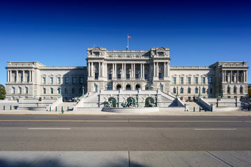 Fototapeta premium Building facade against clear blue sky with main road in foreground.