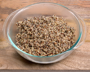 Closeup on glass bowl with cooked tri-color quinoa quinoa on wooden background- quinoa is a pseudograin that has all nine essential amino-acids 