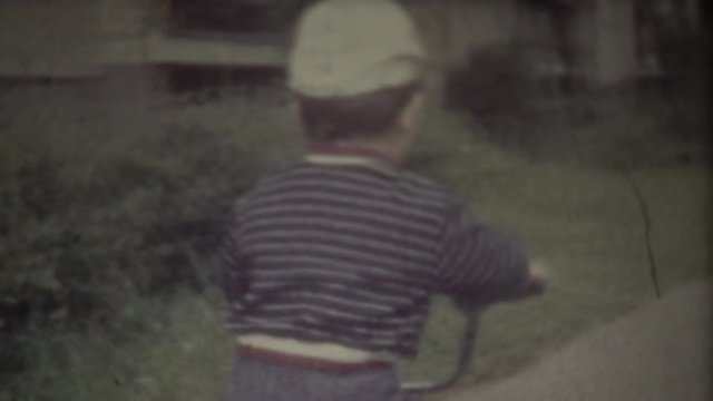 Family Chronicle: Happy toddler riding his bike. Father shooting family video