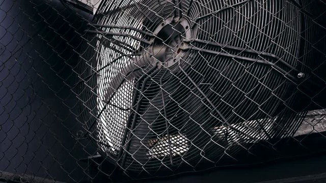 Ventilation fan. Blades of fan of flow-exhaust ventilation system of the building rotate behind the metal mesh.