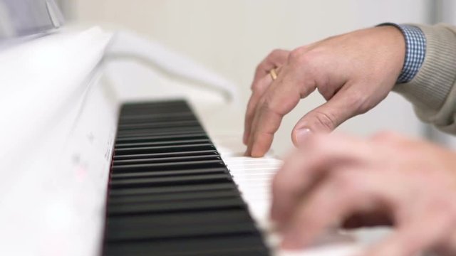 Male hands playing on white piano. Slow motion 120 fps