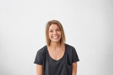 Attractive Caucasian woman with dark shining eyes and bob hairstyle wearing casual T-shirt grinning...