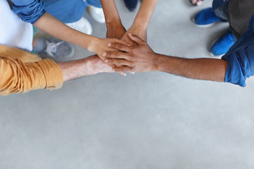 View from above of group of people keeping their hands in pile expressing social friendship, unity,...