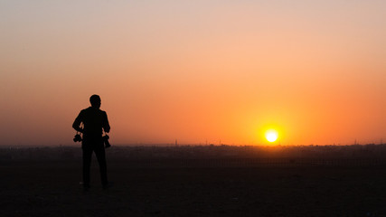 Fototapeta na wymiar Catching the sun setting over Cairo as a photographer searches for his next shot.