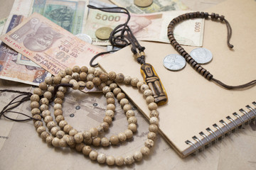Traveling retro still life closeup with map, money, coins, buddhist mala bracelet, diary.