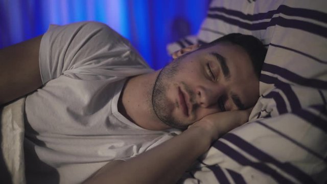 Attractive man sleeping on a bed. 4K
