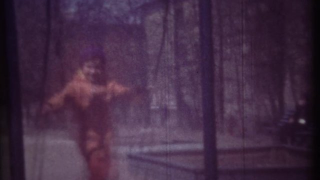 Family chronicle: Little girl child swinging on swing. Her father is recording video on 8 mm retro camera.