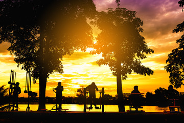 people exercising outdoor with exercise equipment in the park at sunset, silhouette image for abstract background.