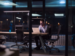 man working on laptop in dark office