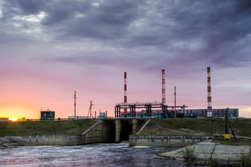 Gas power plant during sunset. Spillway and lake foreground. Energy industry concept.