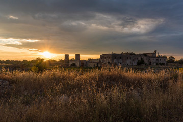 Fototapeta na wymiar Puglia (Italy) - Wind farm with rock ruins, wind turbines and bales of hay at sunset
