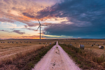 Puglia (Italy) - Wind farm with rock ruins, wind turbines and bales of hay at sunset