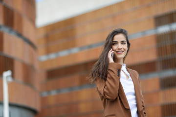 Fototapeta premium Young businesswoman talking with a smartphone in urban background.