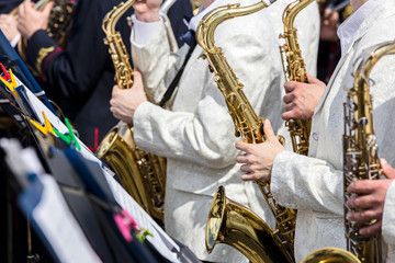 saxophones in the hands of orchestra musicians during street concert