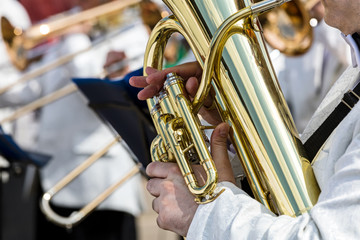 Fototapeta na wymiar hands of a male musician holding big tuba on blurred orchestra background