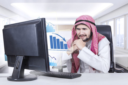 Arabian businessman looks frustrated with declining graph