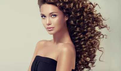 Photo sur Plexiglas Salon de coiffure Fille brune aux cheveux bouclés longs et brillants. Beau modèle avec une coiffure ondulée.
