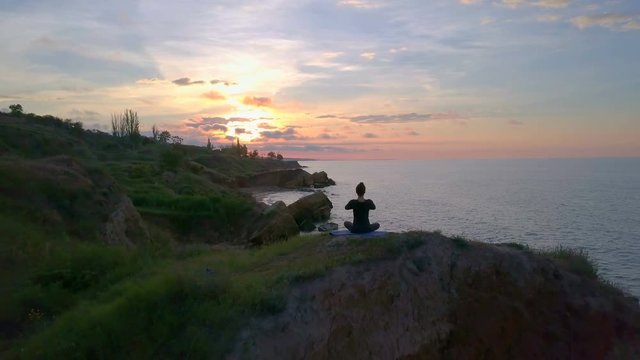 Free young healthy girl doing yoga namaste meditate sunrise coast drone footage