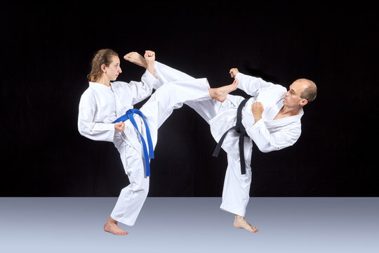 Athletes in karategi are training kicking in pairs
