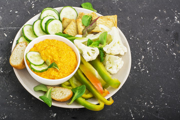 Vegetables bowl of sauce: carrot dip with slices of crispy bread, cucumber, sweet peppers, cauliflower, corn salad on a platter for a large company. Top view