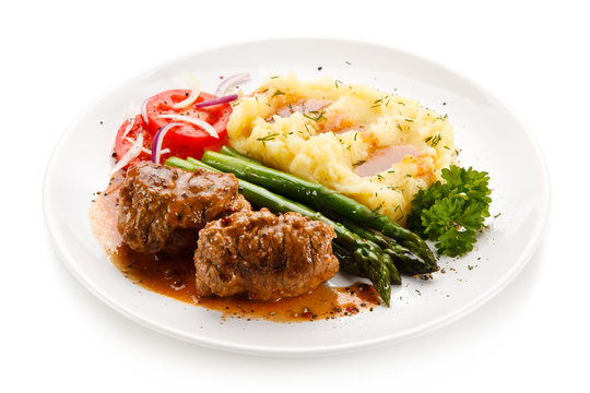 Wrapped pork chops with potatoes and asparagus on white background 