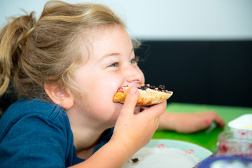 funny girl eating bread roll with marmelade