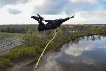 Fototapeta na wymiar Rope jumping from high altitude of bridge. Man fly in air like an airplane.