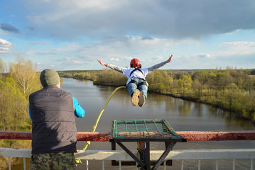 Rope jumping from high altitude of bridge. Brave woman flying in air like a bird.