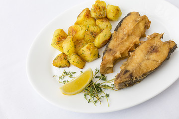 Fried fish garnished with potatoes, close up, top view at restaurant