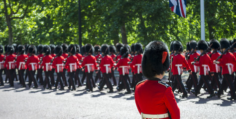 Soldiers in classic red coats march along The Mall in London, England in a grand Trooping the...