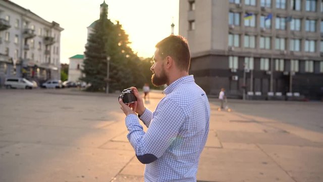 Man is walking around the city and taking photos of sights on a film camera