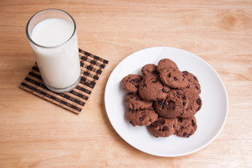 chocolate chip cookie and milk on wooden table