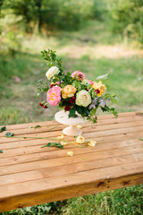 floral design, wedding, romance concept - gorgeous bouquet made of tender avalanches, roses, peonies and dianthuses, decorated with leaves of oak and raspberry-bush, standing in vase on wooden table