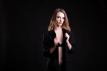 Beautiful blonde in casual fashion clothes in studio photo on black background. Sexyality and sensuality
