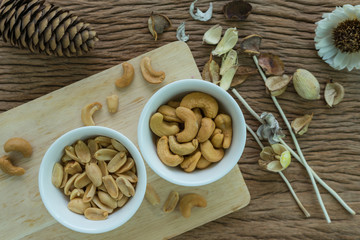 Roasted cashew nuts and peanuts appetizer in white bowl on wooden table background