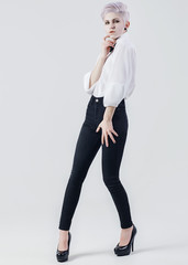 Attractive girl in white shirt and black jeans on white background. Fashion photo. 