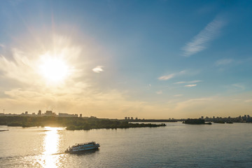 Ship at sunset over a river of skyscrapers in the background
