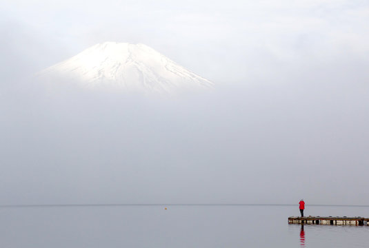alone man in the red coat standing on the bridge in front of Fuji mountain 
