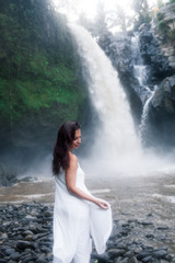 Young Girl in White Clothes Walking near a Waterfall Tegenungan in Bali