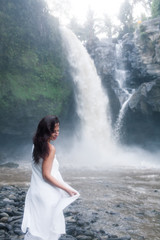 Young Girl in White Clothes Walking near a Waterfall Tegenungan in Bali