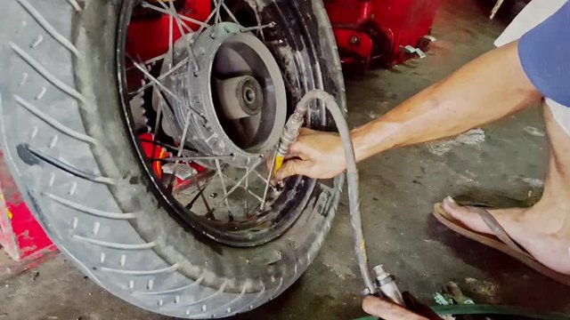 Closeup Man Hands Inflate Scooter Wheel Tire in Shop