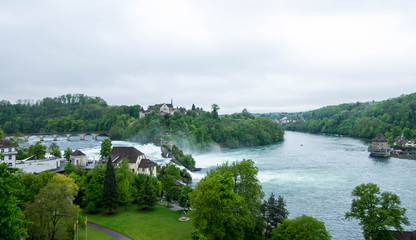 Fototapeta premium Rheinfall landscape. Schloss Laufen on hill, bridge, Worth castle and buildings nearby.
