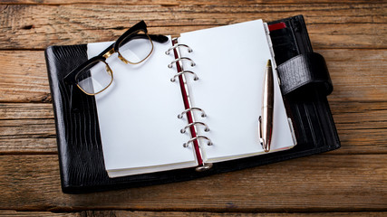 Notebook with pen and glasses on the table.Business Concept .Toned image.Vintage style.Copy space. selective focus.