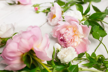 Obraz na płótnie Canvas Close up of pink and white flowers on wooden table. Peonies and wild roses. High key, copy space.