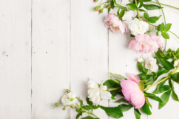 Pink and white flowers on wooden table. Wreath made with peonies and wild roses. High key, copy space.