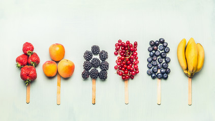 Fruits and berries assorted popsicles on light turquoise background, top view.Healthy food and vegetarian eating concept