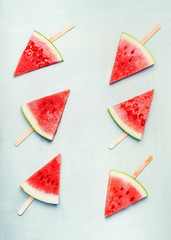 Watermelon slice popsicles on light turquoise background, top view, flat lay. Healthy food and vegetarian eating concept