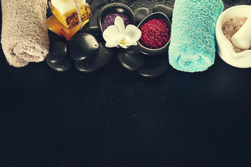 Beautiful Spa Set Spa Products with Essential Oils, Soap, Towel, Spa Sea Salt on Dark Wet Background. Horizontal with Copy Space.