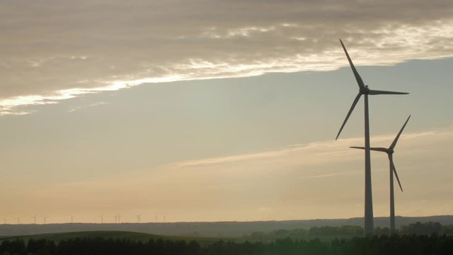 Wind turbine farm with rays of light at sunset, Europe.